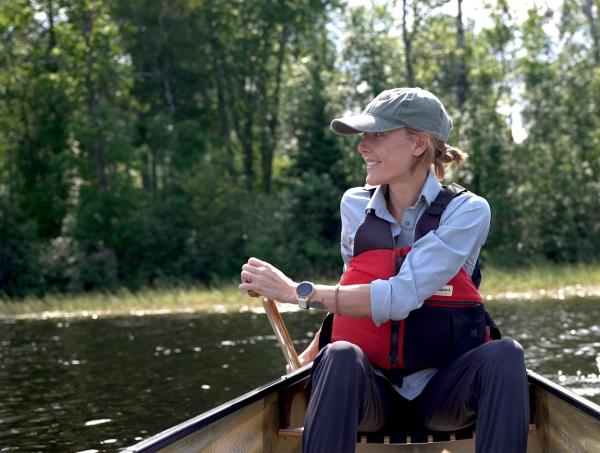 Ingrid Paddling a canoe in the Boundary Waters with a green hat looking into tthe dista