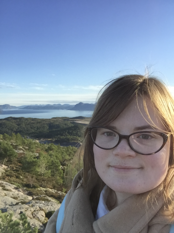 Katilynn in front of mountains and a water body