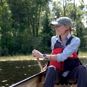 Ingrid Paddling a canoe in the Boundary Waters with a green hat looking into tthe dista