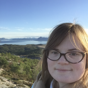 Katilynn in front of mountains and a water body