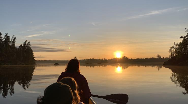 Photo of 3 people paddling into the sunrise