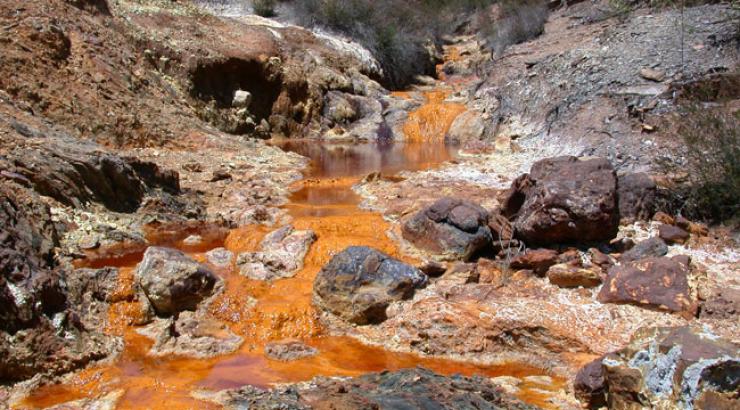Orange, polluted water flowing down a waterfall