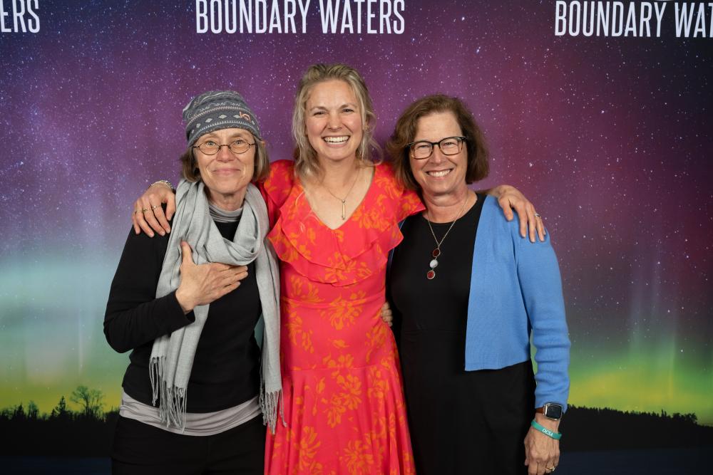 three people posing in front of northern lights backdrop