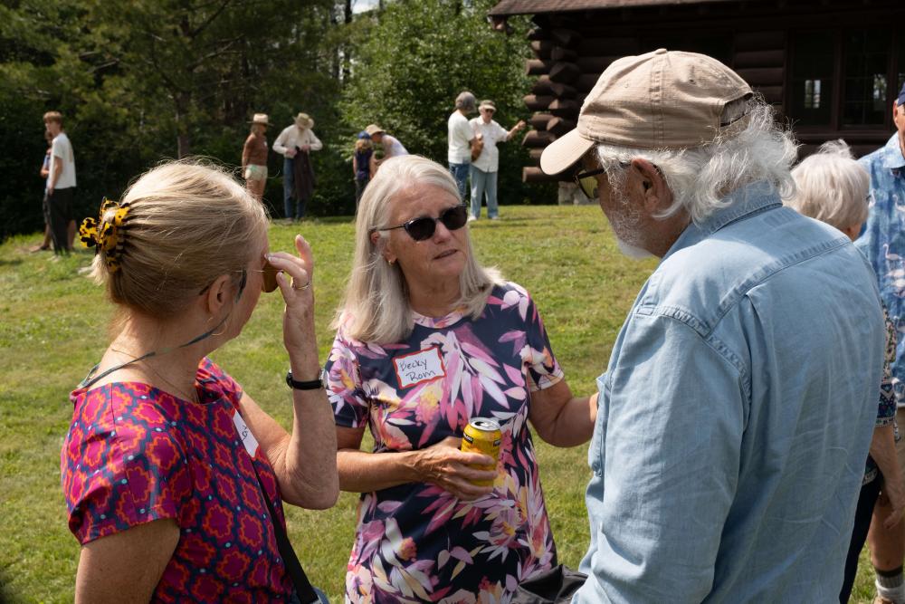 Board member Becky Rom talking to two people at the garden party