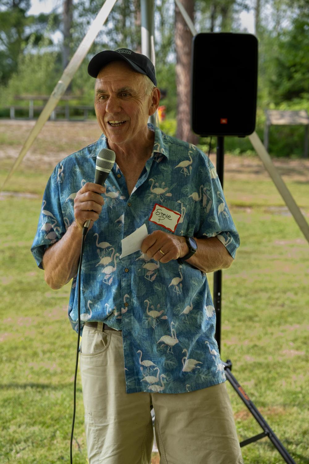 Board member Steve Piragis speaking to the crowd at the garden party