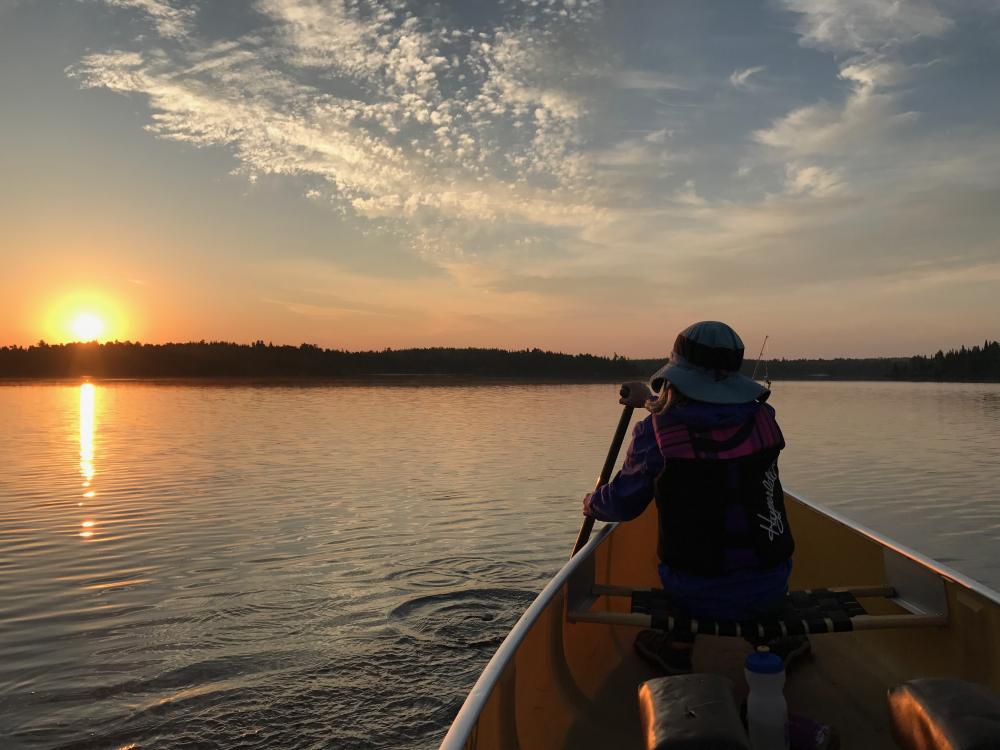 Kid canoes at sunset