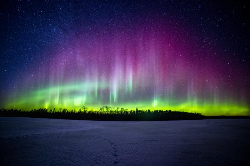 aurora with purple and green lights over a frozen lake 